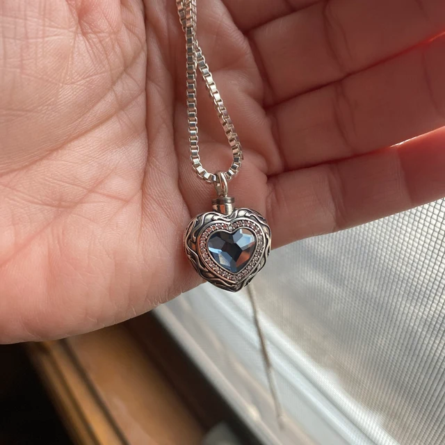 Customer photo of the Blue Heart cremation necklace held near a window